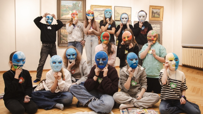 bērni izstāžu zālē pozē ar apgleznotām maskām uz sejas