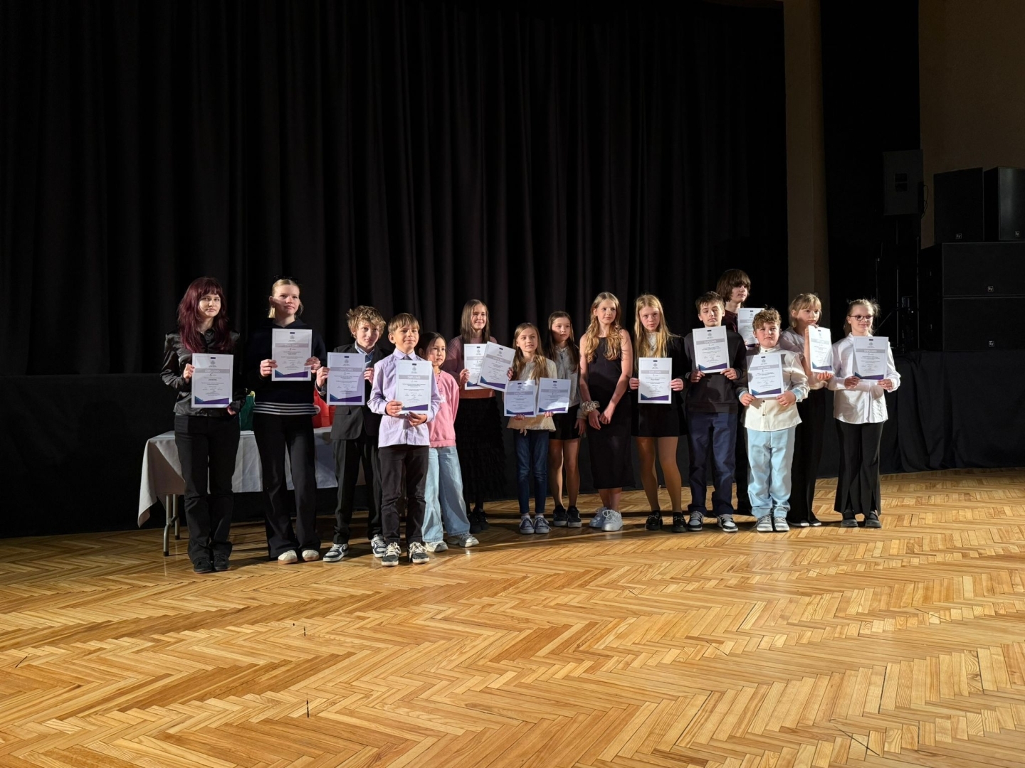 jaunieši ar diplomiem pie skatuves